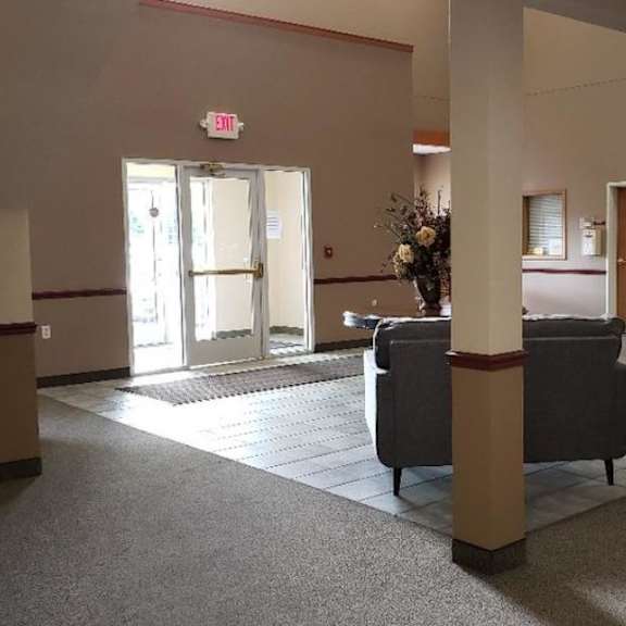 a spacious room with a grey carpet and furniture including a sofa and a chair.