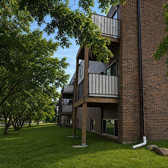 a brick building with a balcony and a tree in front.