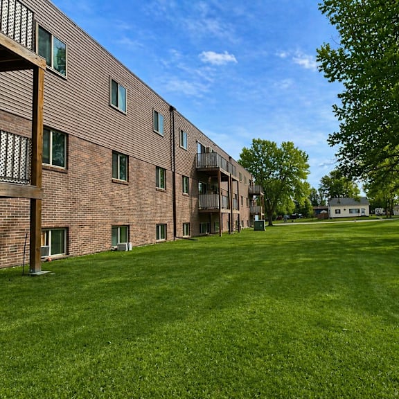 a grassy area in front of a building with trees.
