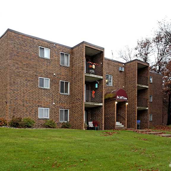 a brick apartment building with a green lawn in front.