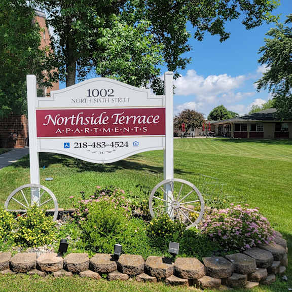a sign for northside terrace apartments is displayed in front of a landscaped area.