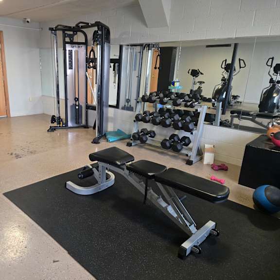 a gym with a variety of equipment including a treadmill, weights, and a bench.