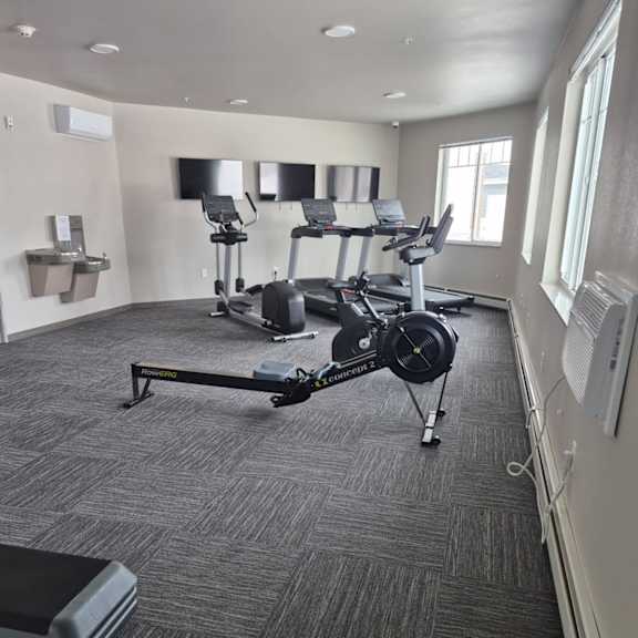 a gym with a row of treadmills and elliptical machines.