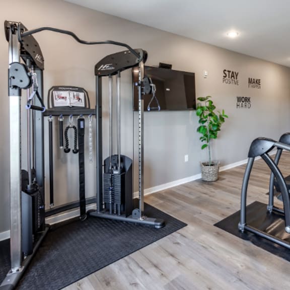a gym with a row of treadmilers and a wall with the words "stay positive, make work hard".
