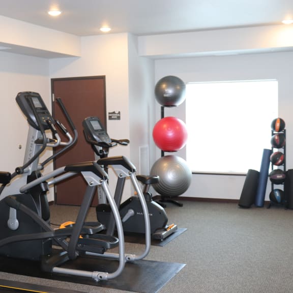 a gym with two exercise machines and a yoga ball on the floor