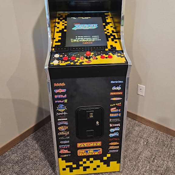 a small arcade machine with a black background and yellow and black pixelated design.