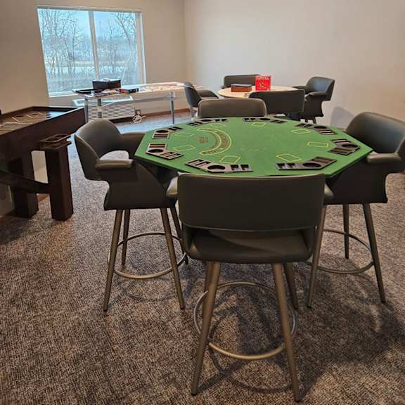 a poker table surrounded by chairs in a room.