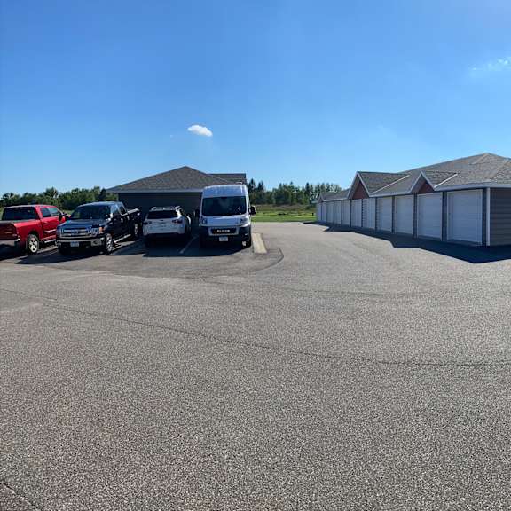 a parking lot with several cars and a few buildings in the background.