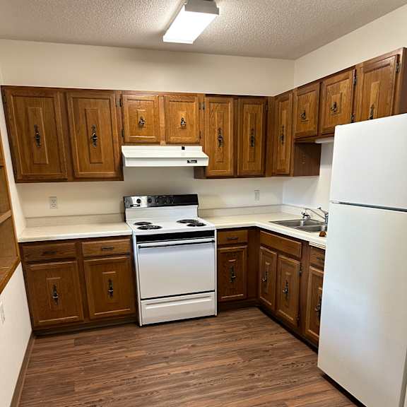 a small kitchen with a refrigerator and wooden cabinets