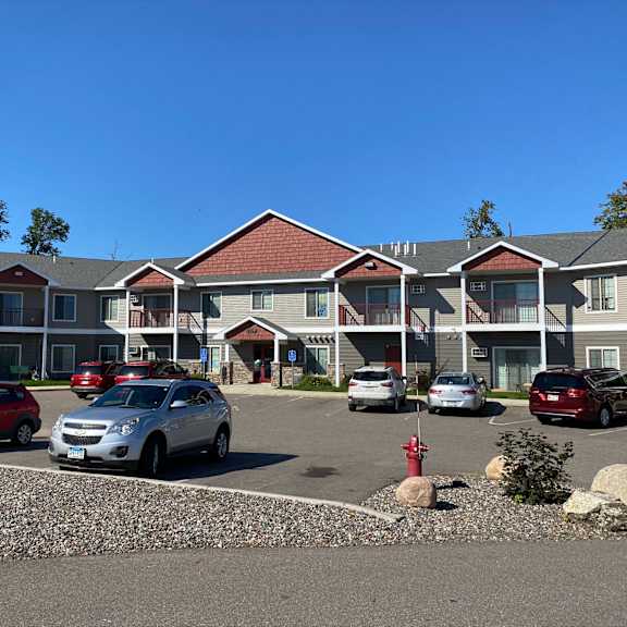 a parking lot in front of a building with cars parked.