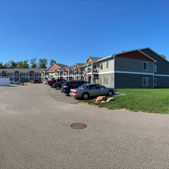 a residential street with houses on both sides and cars parked on the right.