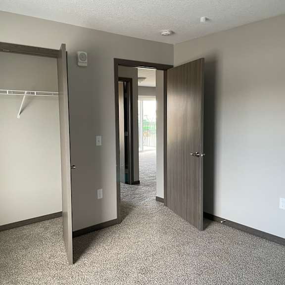 an empty bedroom with a closet and two doors