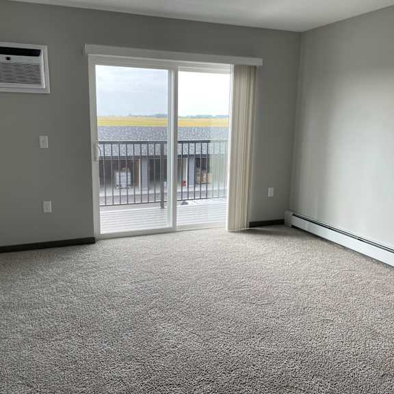 an empty living room with a door to a balcony