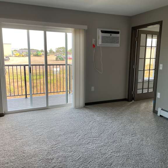 an empty living room with a sliding glass door to a balcony