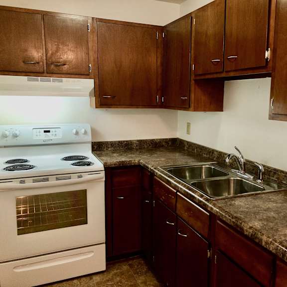 a kitchen with a white stove and brown cabinets.