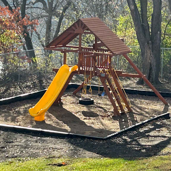 a wooden playground with a yellow slide.