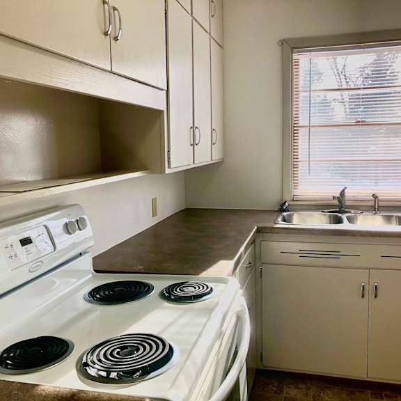 a white stove with four burners is in a kitchen with white cabinets.