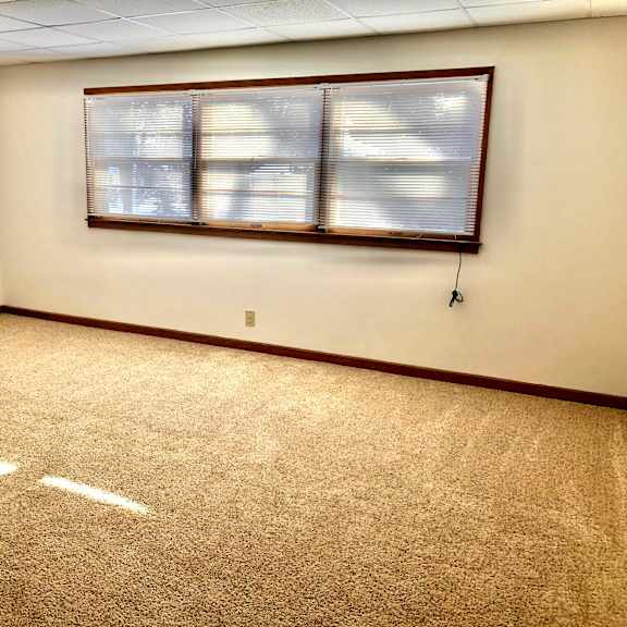 a room with a carpeted floor and a window with blinds.