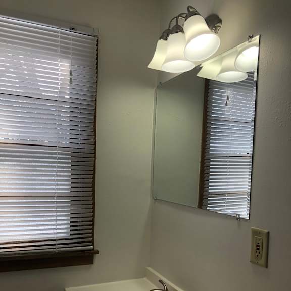 a bathroom with a sink and a window with blinds.
