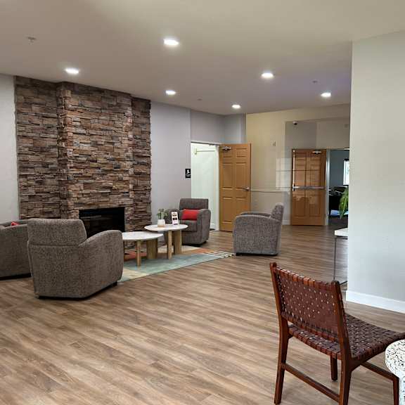 a living room with a stone fireplace and a wooden chair.