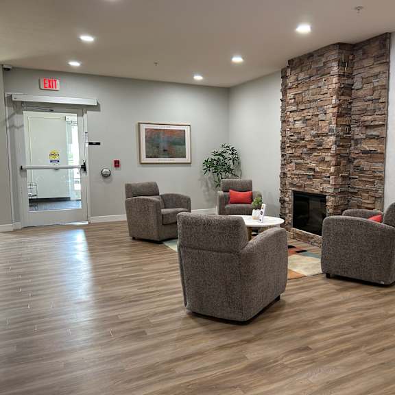 a room with a stone fireplace and grey chairs.