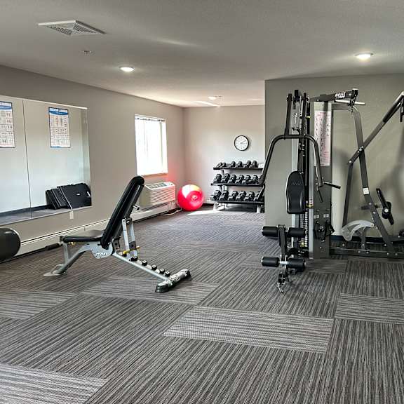 a gym with a variety of equipment including a leg press machine, a chest press machine, and a weight rack.