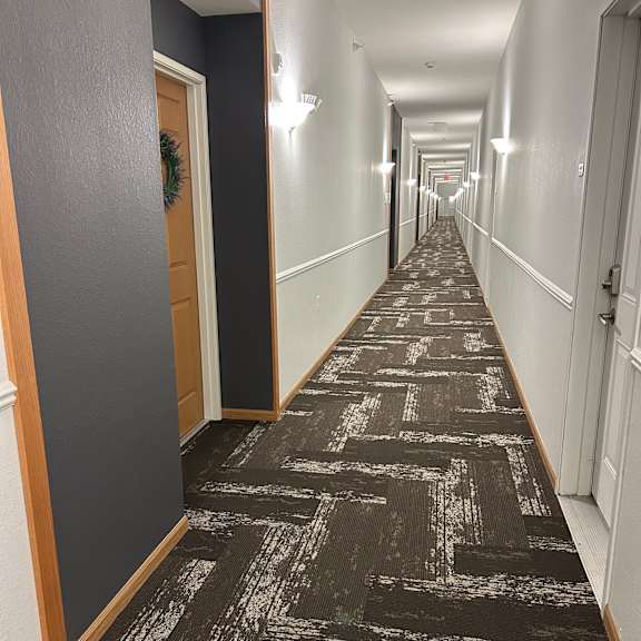 a long, narrow hallway with a black and white patterned wallpaper.
