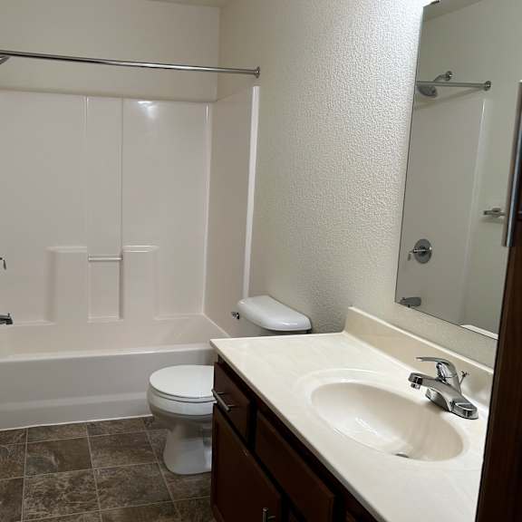 a white bathroom with a toilet, sink, and bathtub.
