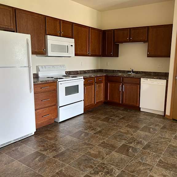 a kitchen with brown cabinets and a white refrigerator.