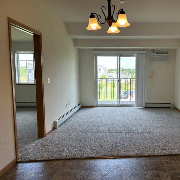 a spacious room with a carpeted floor and a chandelier hanging from the ceiling.