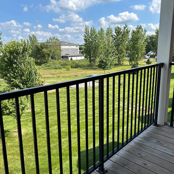a balcony with a black railing overlooks a green lawn.