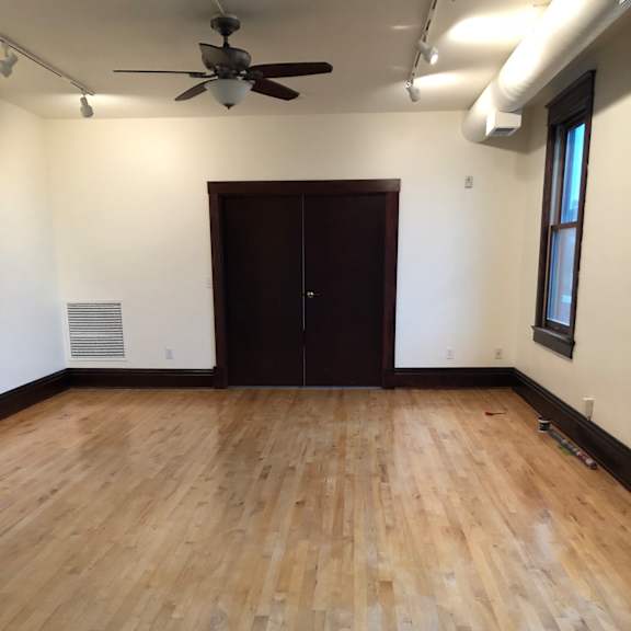 a room with a ceiling fan and wooden flooring.