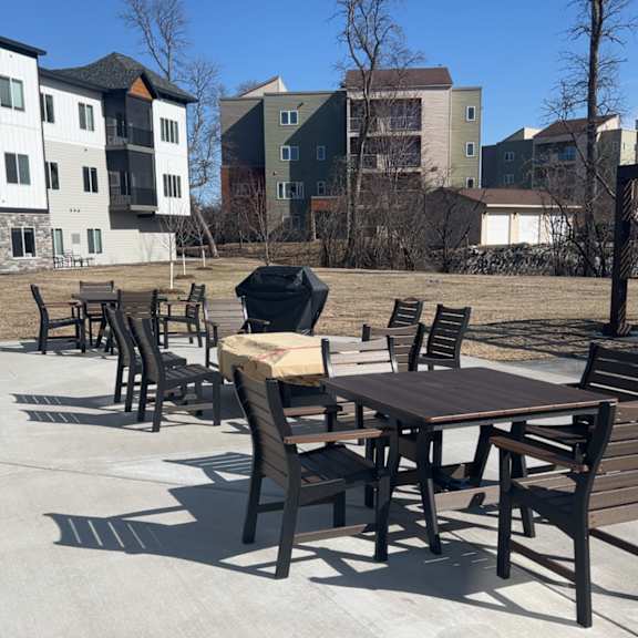 a park with a table and chairs in the foreground and apartment buildings in the background.