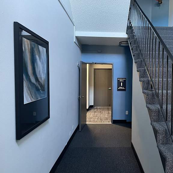 a staircase with a metal railing and a grey carpeted floor.