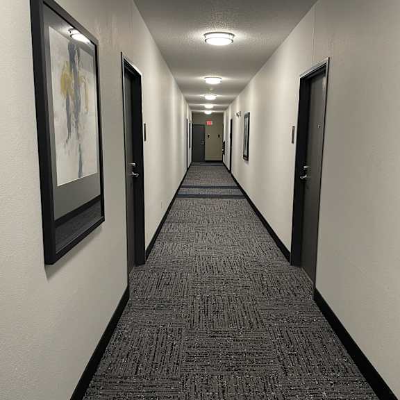 a hallway with carpeted flooring and framed artwork on the walls.