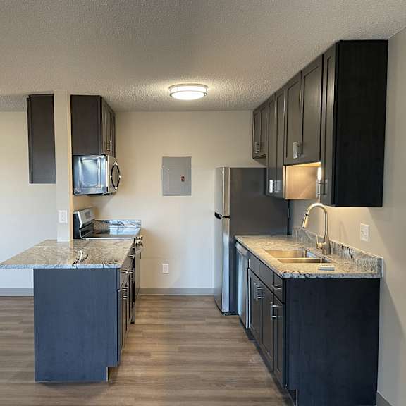a kitchen with dark wood cabinets and a granite countertop.