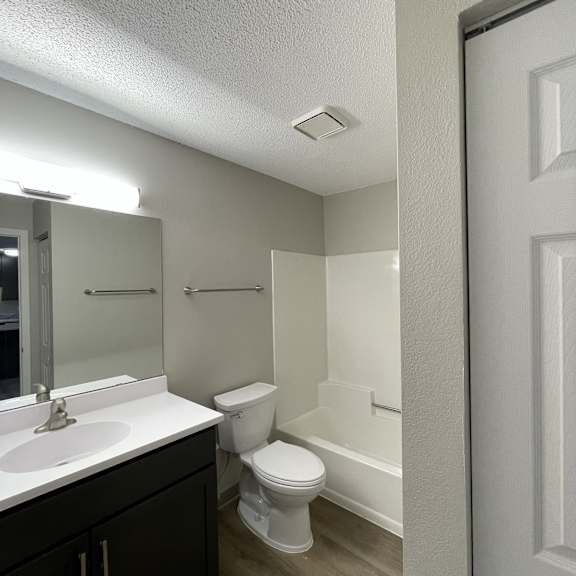 a white toilet sits in a bathroom next to a sink and a bathtub.