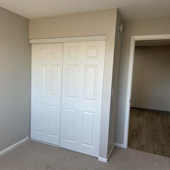 a white double door is in a room with a carpeted floor.
