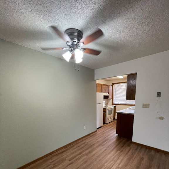 a room with a ceiling fan and wooden flooring.