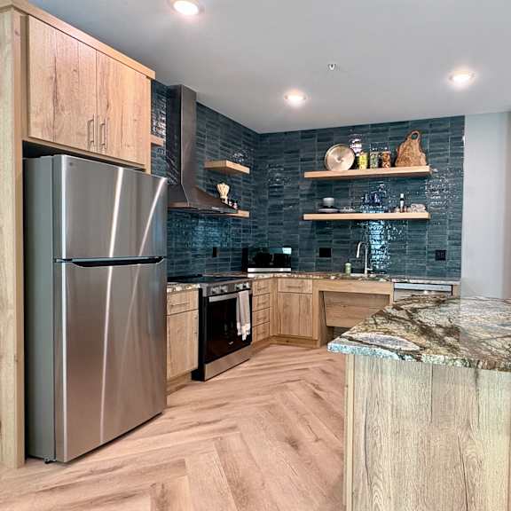 a modern kitchen with a marble countertop and wooden cabinets.