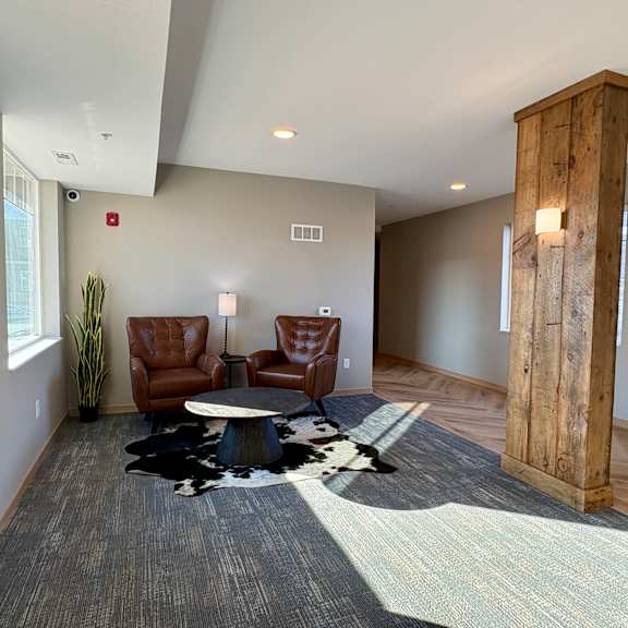 a room with a wooden column and two brown leather chairs.