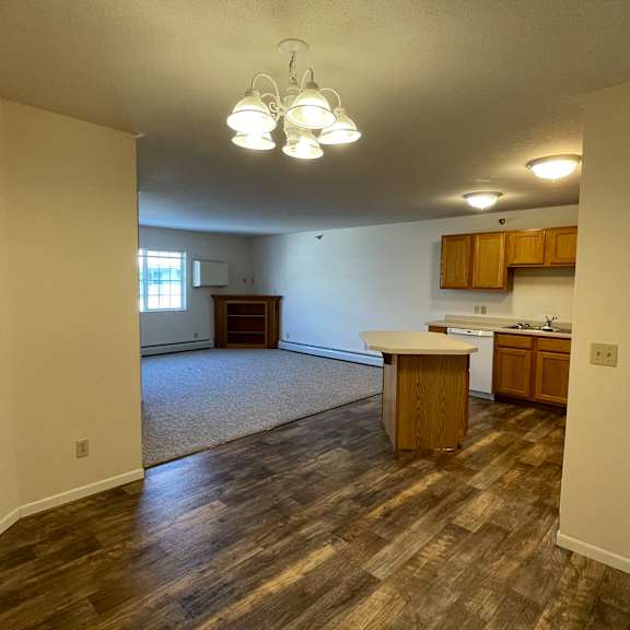a room with wooden floors and a kitchenette.