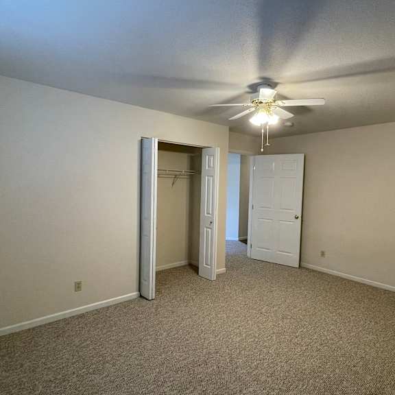 a room with a ceiling fan and carpeted floor.