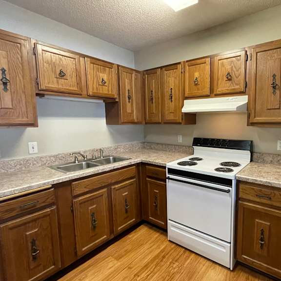 a kitchen with wooden cabinets and a white stove top oven.