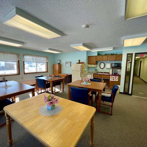 a room with tables and chairs and a vase of flowers on the table.
