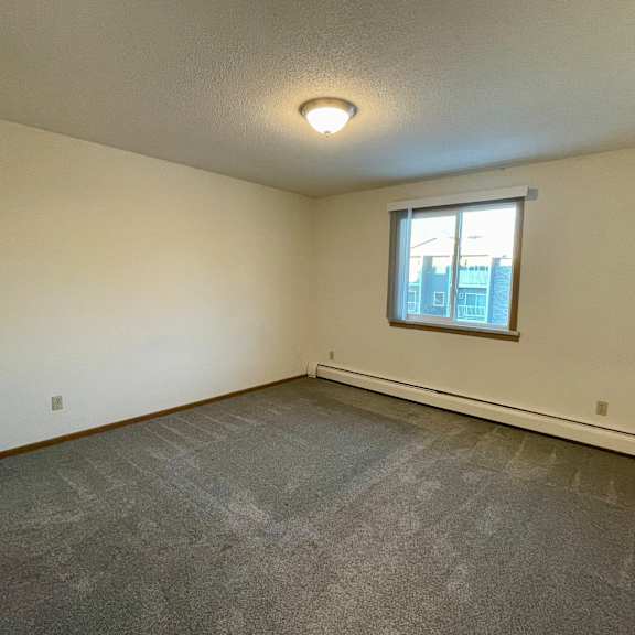 a room with a window and a grey carpet.