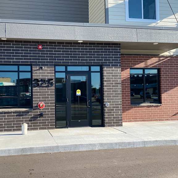 a brick building with glass doors and a sidewalk