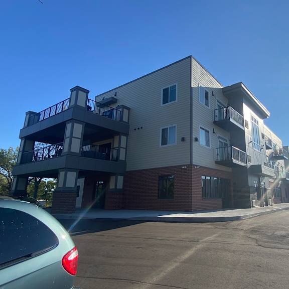 an apartment building on a street with the sun shining in the sky