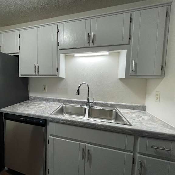 a kitchen with a black refrigerator and a marble counter top.