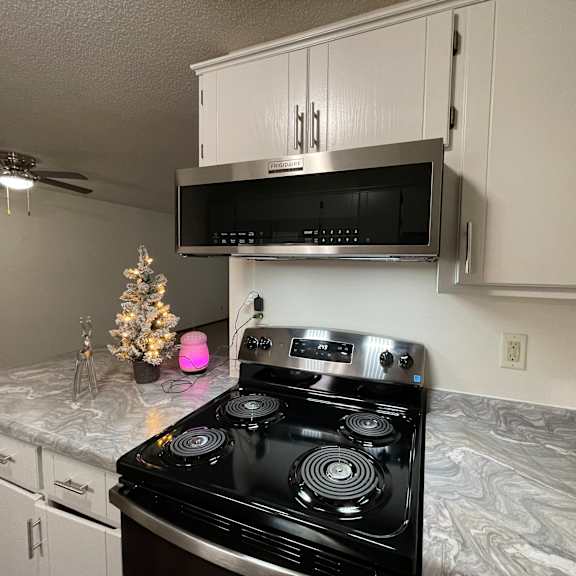 a black stove top oven in a kitchen with a pink light on.